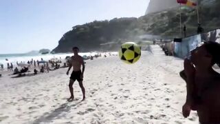 Aksi juggling bola di tepi pantai dengan suasana cerah dan penuh keramaian,