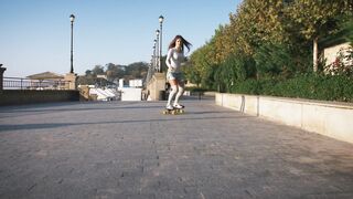 young stylish woman skateboarding
