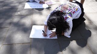 Woman Within - woman writing on sidewalk during daytime protest | Trending HD Video