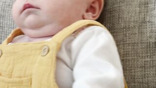 Babymoov - a baby sitting on a couch | Trending HD Video