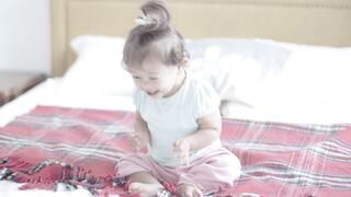 Babymoov - smiling baby girl sitting on bed | Trending HD Video