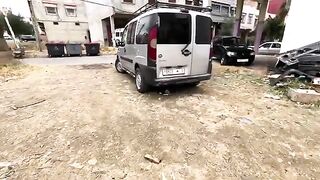 Tuxedo cat is relaxing under the car enjoying a delicious dish.