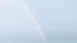 Travelpro - a rainbow is seen over the ocean from a hill | Trending HD Video