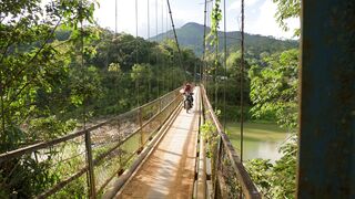 Travelon - two people on a motorbike crossing a bridge in a mountain area | Trending HD Video