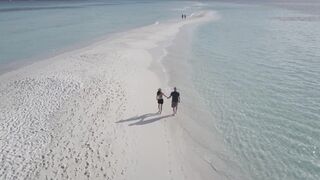 Couple Walking on a Beach Filmed with a Drone