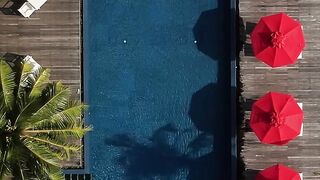 travelite - aerial view of luxurious pool with red umbrellas | Trending HD Video