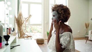 Wonder Woman - a woman looking in the mirror while applying a sheet mask | Trending HD Video