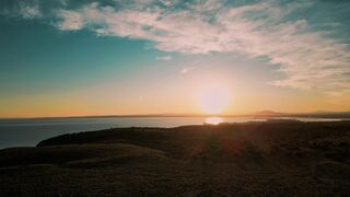 Travel Backpack - the sun setting over the ocean and hills | Trending HD Video