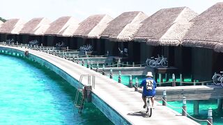 Travelon - cyclist riding along overwater villas in maldives | Trending HD Video