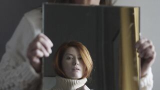 The Pioneer Woman - a woman holding a mirror with a reflection of another woman in beige sweate
