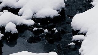 Winter solstice - snow covered rocks by a flowing creek | Trending HD Video