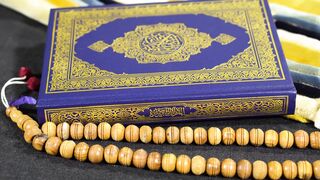 ALIEN STAGE the Art Book Deluxe Edition - close up of the quran holy book and a wooden rosary |