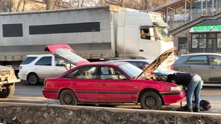 Carrefour - mechanic repairing car on busy street | Trending HD Video