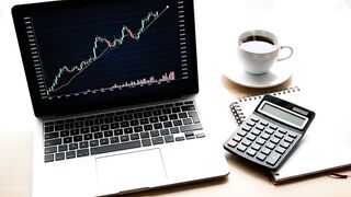Stock Market Analysis on Laptop with Coffee and Calculator
