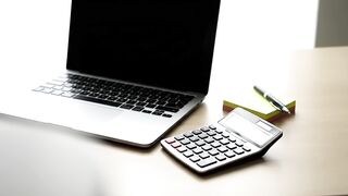 Modern Office Workspace with Laptop, Calculator, and Stationery