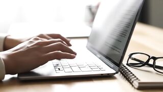 Close-Up of Hands Typing on Laptop at Professional Desk