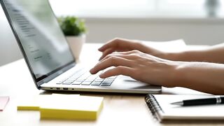 Person Typing on Laptop in Professional Workspace