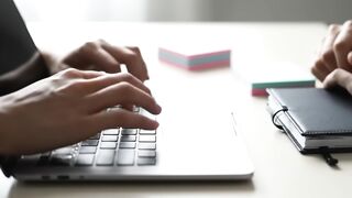 Close-Up of Hands Typing on Laptop Keyboard in Office