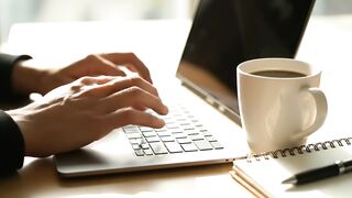 Person Typing on Laptop in Modern Office Workspace