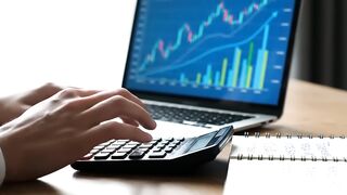 Financial Analyst Using Calculator for Stock Market Investment