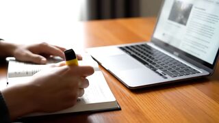 Person Studying with Laptop and Highlighter at Desk