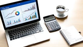 Professional Financial Workspace with Data Charts on Laptop and Calculator