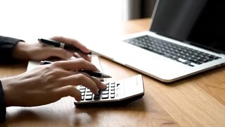 Business Person Calculating Financial Data with Laptop and Calculator