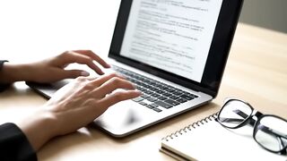 Professional Hands Typing on Laptop at Modern Office Workspace