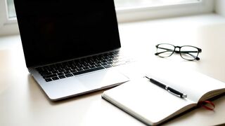 Professional Workspace with Laptop and Hand Turning Notebook Page