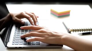 Close-Up of Hands Typing on Laptop Keyboard in Modern Workspace