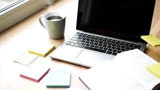 Modern Professional Workspace with Laptop, Open Book, Coffee, and Sticky Notes