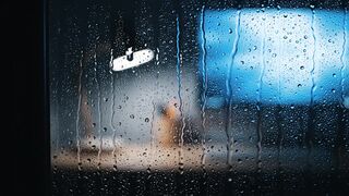 Raindrops on Window Pane with Blurred City Night Lights