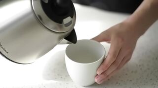 Pouring Fresh Coffee into a White Ceramic Cup