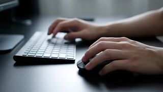 Hands Operating Wireless Keyboard and Mouse on Dark Desk
