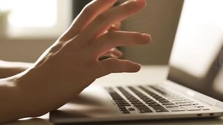 Hands Gesturing Over Laptop in a Modern Office Setting