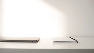 Minimalist Workspace with Closed Laptop and Notebook on White Desk