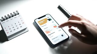 Person Using Smartphone for Digital Planning and Scheduling on White Desk