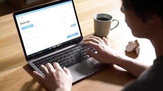 Hands Using Laptop at Wooden Desk with Coffee