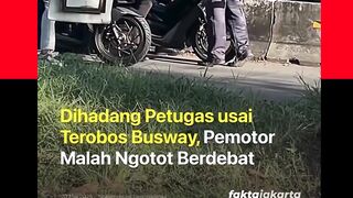 Seorang petugas penjaga palang jalur TransJakarta menghadang pemotor yang nekat