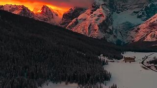 De manhã cedo, em uma paisagem coberta de neve, um sol escaldante surge por trás das montanhas ????