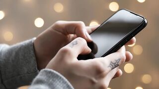 Smartphone usage close up showing hands with tattoos