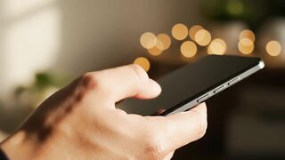 Smartphone interaction video showing person scrolling screen with bokeh background