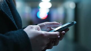 Woman using smartphone searching internet motion video in dark corridor