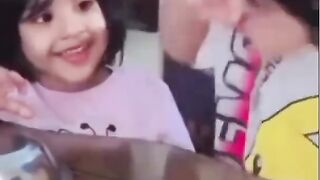 Cute young girl looking curiously at a food bowl while sitting indoors.