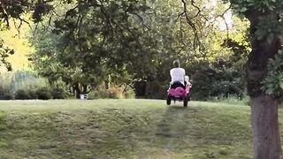 Small toy vehicle placed on a grassy field with a rustic wooden hut nearby.