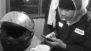 Night Shift Security Guard Checking Smartphone in Guardhouse CCTV Style