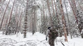 Bushcraft in a snowstorm. Building a warm and cozy shelter from branches under a spruce tree