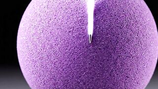 Purple wax sphere candle lit on black stand with bright flame for relaxation and decor