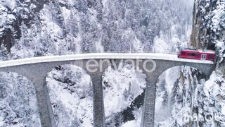 Landwasser Viaduct with Railway and Train in Winter. Snowing. Swiss Alps.
