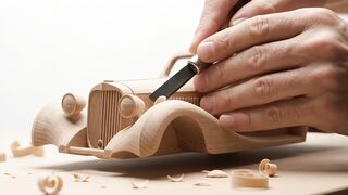 Craftsman carving classic car miniature in wood